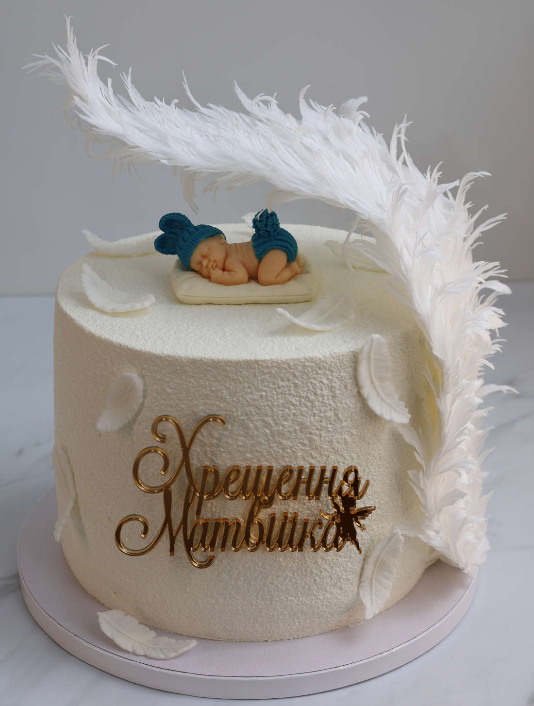 Christening cake with a chocolate baby and an angel wing