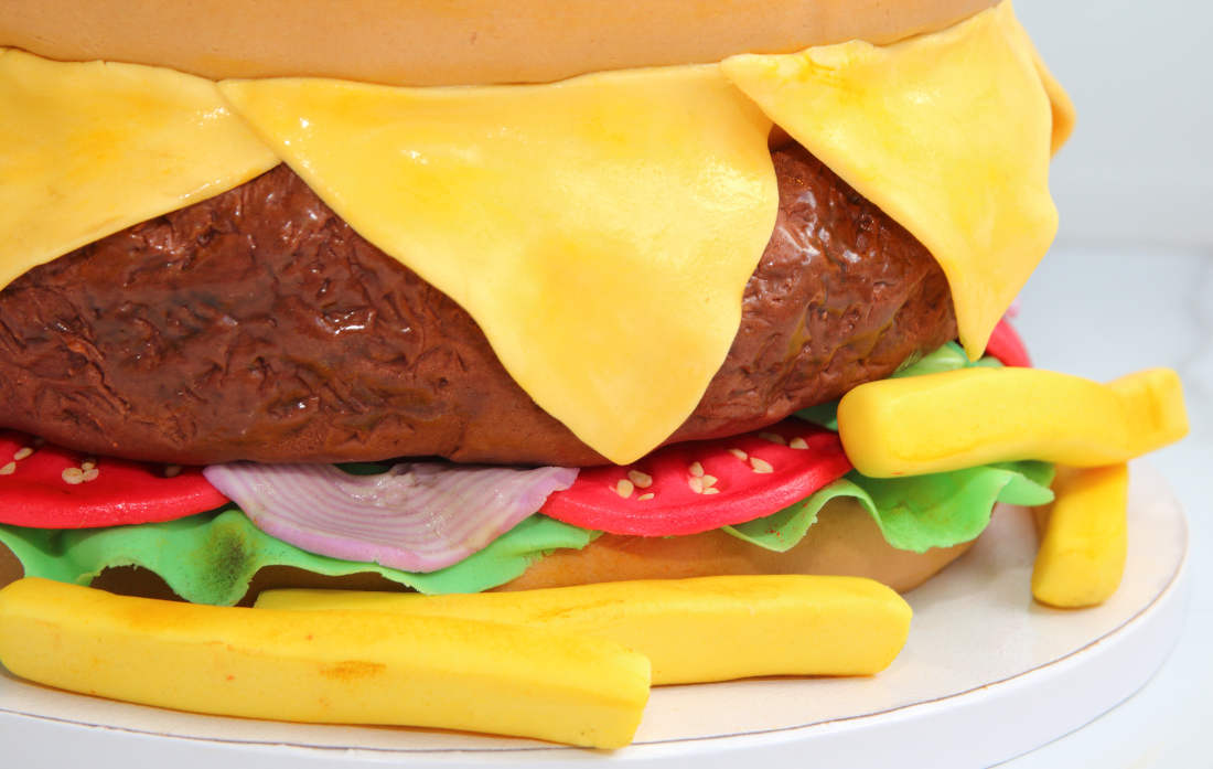 Sweet burger cake with meat, cheese, onions, tomatoes and french fries