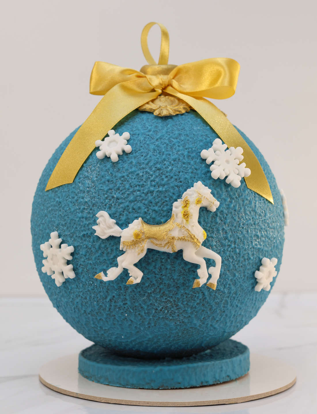 Blue cake with a yellow bow, snowflakes and a horse