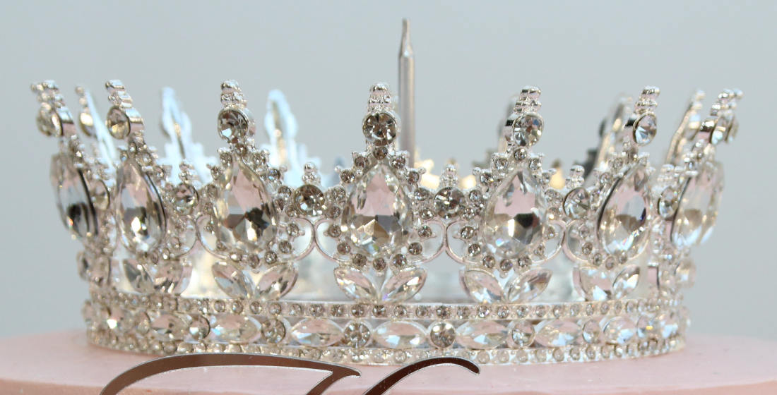 Silver crown with diamonds on a cake with a candle