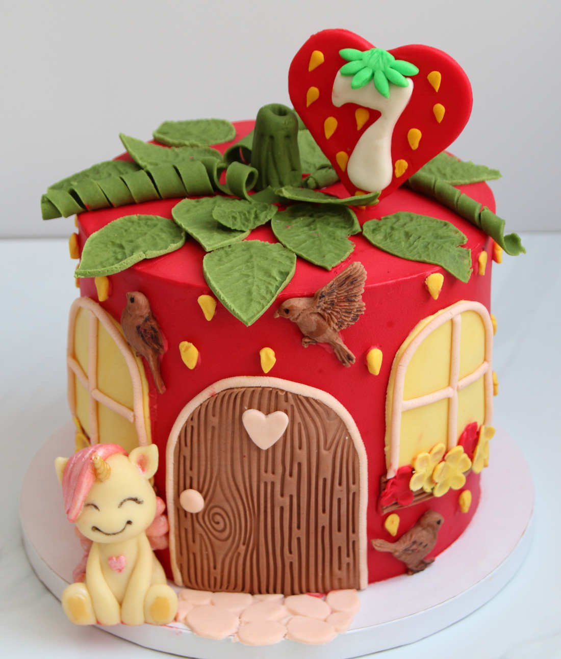 Fairytale house cake in the form of strawberries with a unicorn and birds