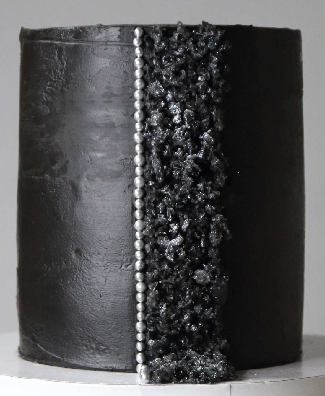 Decorations of isomalt pieces and sugar balls on a black birthday cake