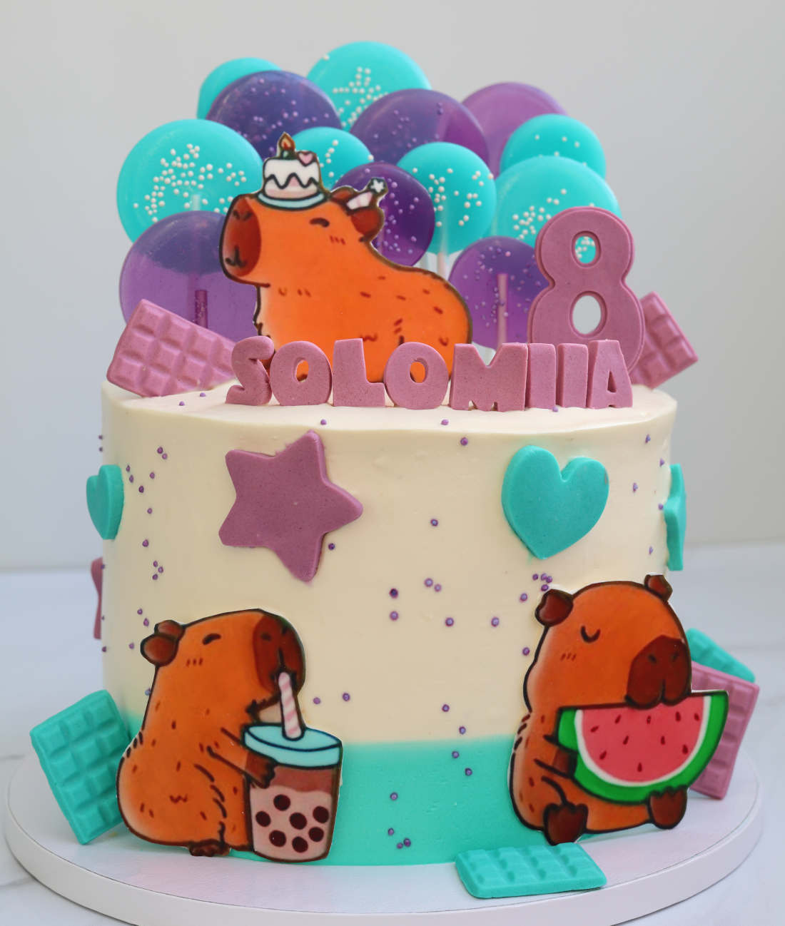 Capybara with the cake on its head and colorful lollipops