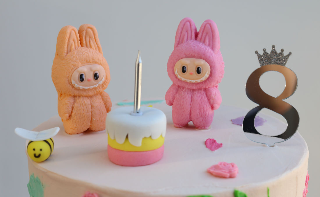 Labubu toys near a small cake with the candle