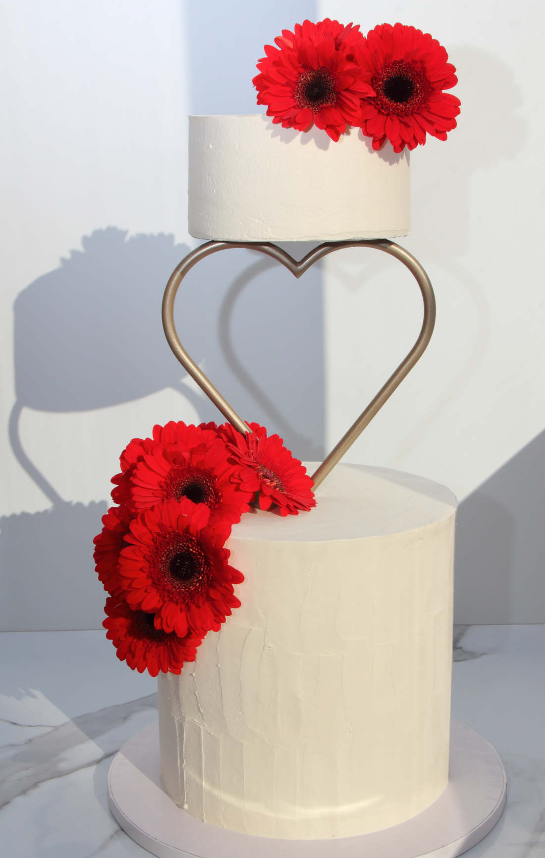 Two-tier wedding cake with a heart and flowers
