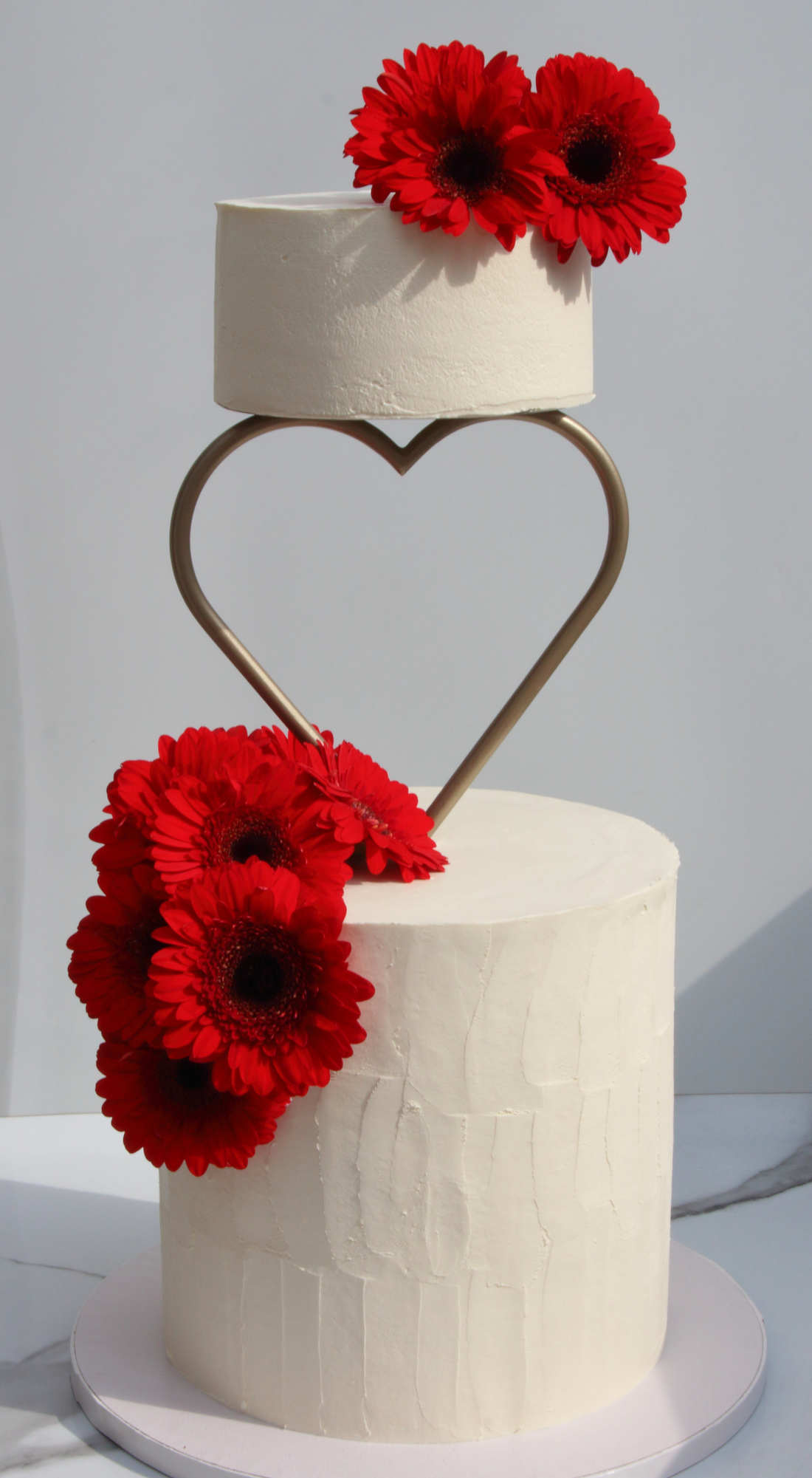 Two-tier wedding cake with a heart and flowers
